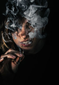 Portrait of woman smoking cigarette on black background