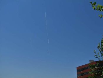 Low angle view of vapor trail against clear blue sky