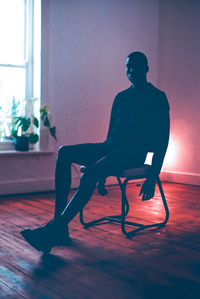 Silhouette man sitting on chair at home