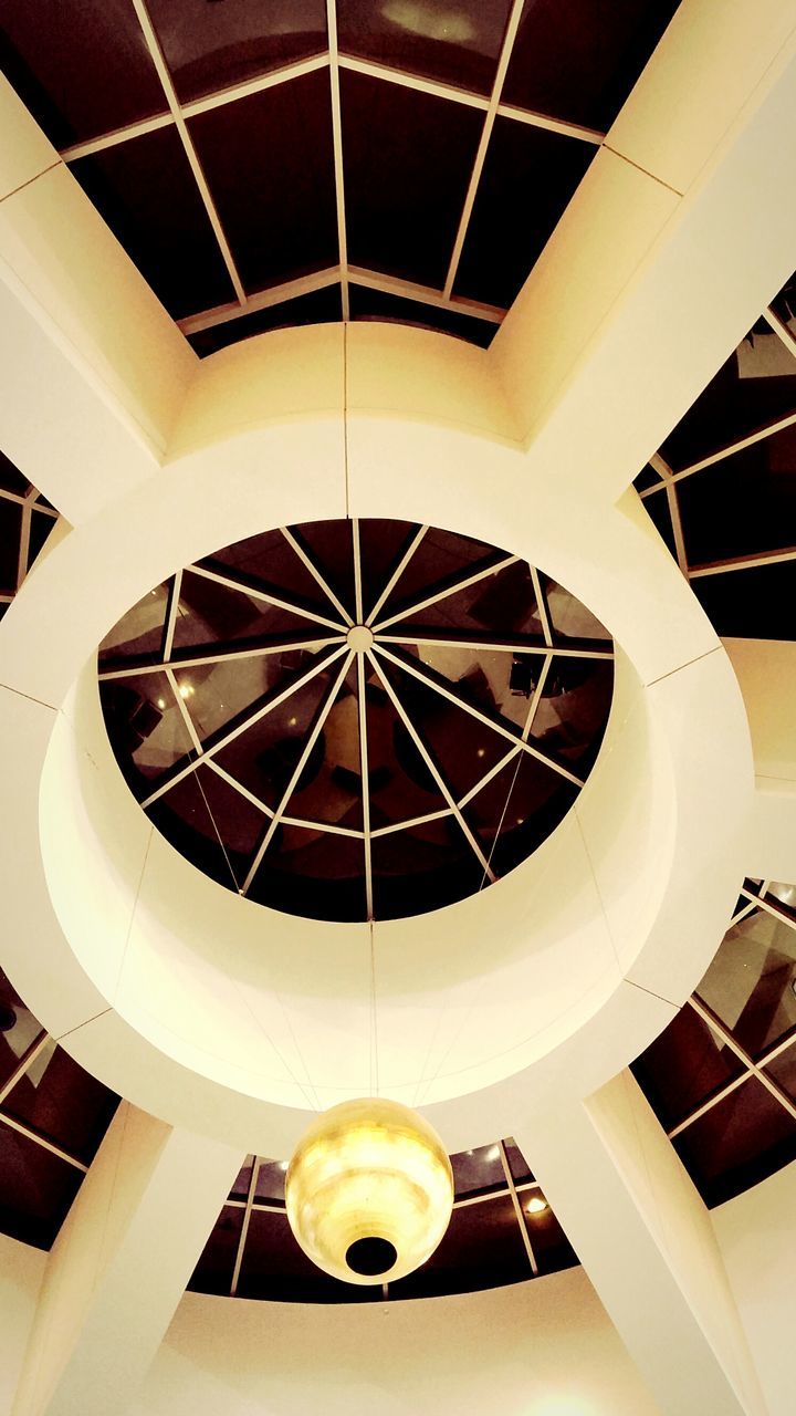indoors, ceiling, low angle view, architecture, built structure, directly below, illuminated, modern, circle, skylight, architectural feature, lighting equipment, geometric shape, pattern, design, shape, hanging, building, no people, pendant light