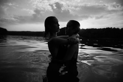 Rear view of mother and daughter in swimming pool against sky