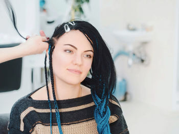 Cropped hand of hairdresser styling female costumer hair