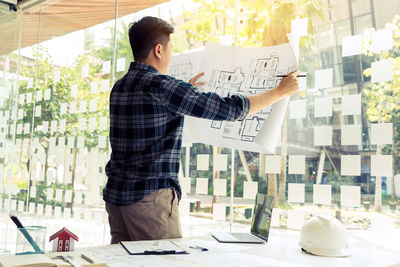 Midsection of man holding paper while standing on table