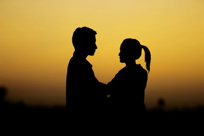 Silhouette couple against orange sky during sunset