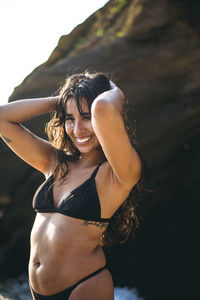 Young latina woman laughing by the ocean at golden hour in summertime