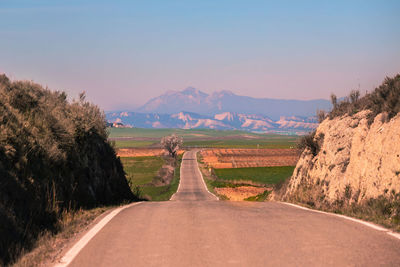 Empty road amidst landscape against sky