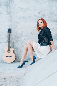 Full length of young woman sitting on wall