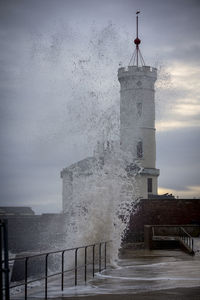 Lighthouse by sea against sky