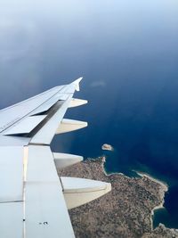 Close-up of airplane wing over sea against sky