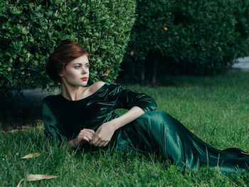 Young woman looking away while lying on grass