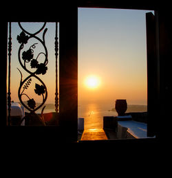 Silhouette building by sea against clear sky during sunset