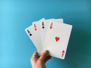 High angle view of man with three aces cards on blue table