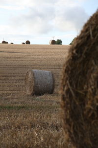 Hay bales on field against sky