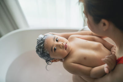 Midsection of mother bathing baby