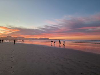 Silhouette people at beach against sky during sunset