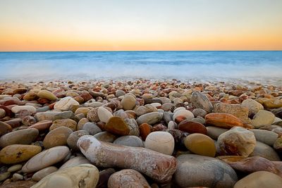 Rocks at beach against sky during sunset