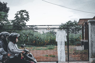 Side view of man standing by railing against sky