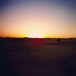 Scenic view of desert against clear sky during sunset