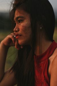 Close-up of young woman standing against sky during sunset