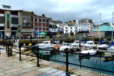 Yachts moored in sea against buildings in city