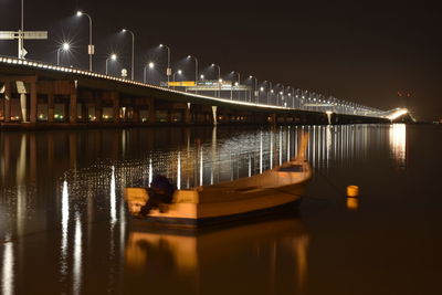 Illuminated bridge over river against sky at night