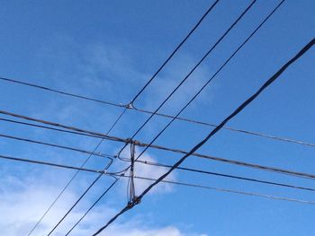 Low angle view of electricity pylon against blue sky