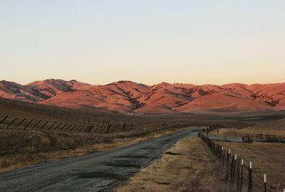 Road amidst desert against clear sky