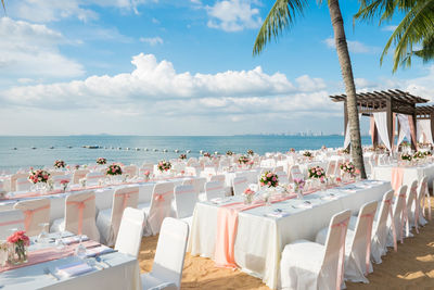 Chairs and tables at beach against sky