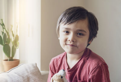 Portrait of cute boy sitting against wall at home