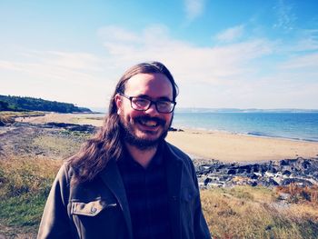 Portrait of young man standing against sea