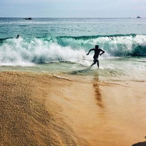 Man running by wave at beach