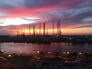 Illuminated harbor against sky at sunset