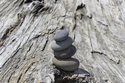 A cairn of four smooth stones balanced atop a large driftwood log in la push, washington, usa.