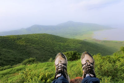 Low section of man on mountain against sky