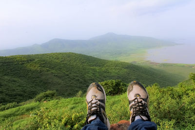 Low section of man on mountain against sky