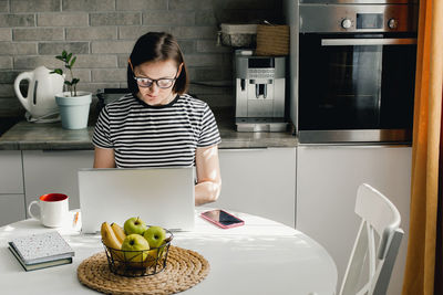 Portrait of young woman using laptop on table