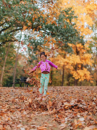 Full length of girl standing on tree during autumn