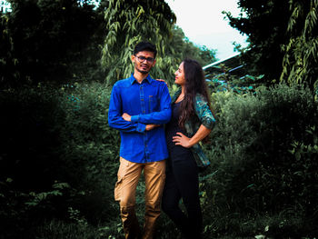 Young couple standing against trees