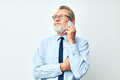 Senior man talking on phone against white background