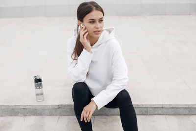 Young woman talking on phone while sitting outdoors