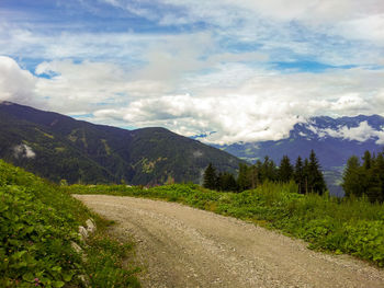 Mountain road in alpine landscape with cloudy sky in luesen, italy. view from mountain peak