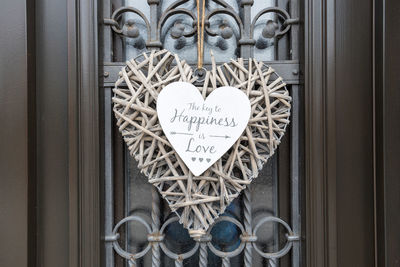 A wicker heart hanging on the door with happiness and love quote