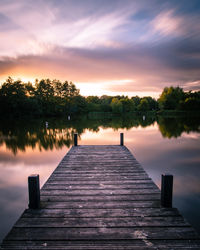 Pier over lake against sky during sunset