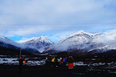 People on snowcapped mountains against sky