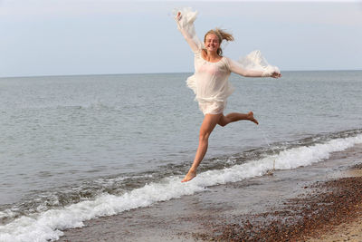 Full length of young woman jumping on beach