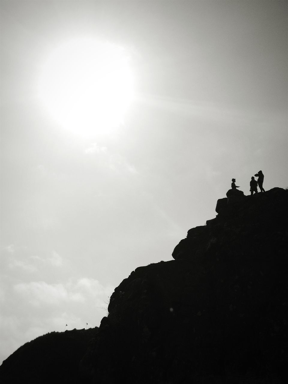 silhouette, low angle view, built structure, sky, architecture, building exterior, sun, sunlight, lifestyles, men, leisure activity, sunbeam, copy space, lens flare, outdoors, unrecognizable person, clear sky, day