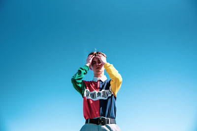 Low angle view of man standing against clear blue sky