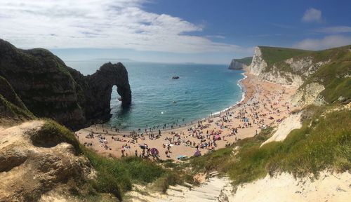 High angle view of people at jurassic coast by durdle door against cloudy sky