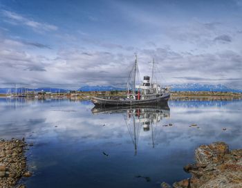 Boats in harbor against cloudy sky