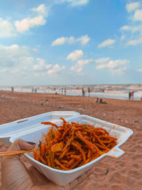 Close-up of food on beach against sky